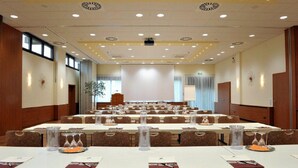 Ein Konferenzraum mit mehreren Tischen, Stühlen und einer Projektionsleinwand.