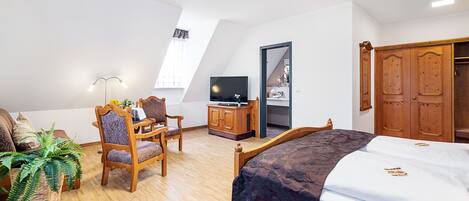 A bedroom with a bed, a desk, a chair, a television, and a wardrobe.