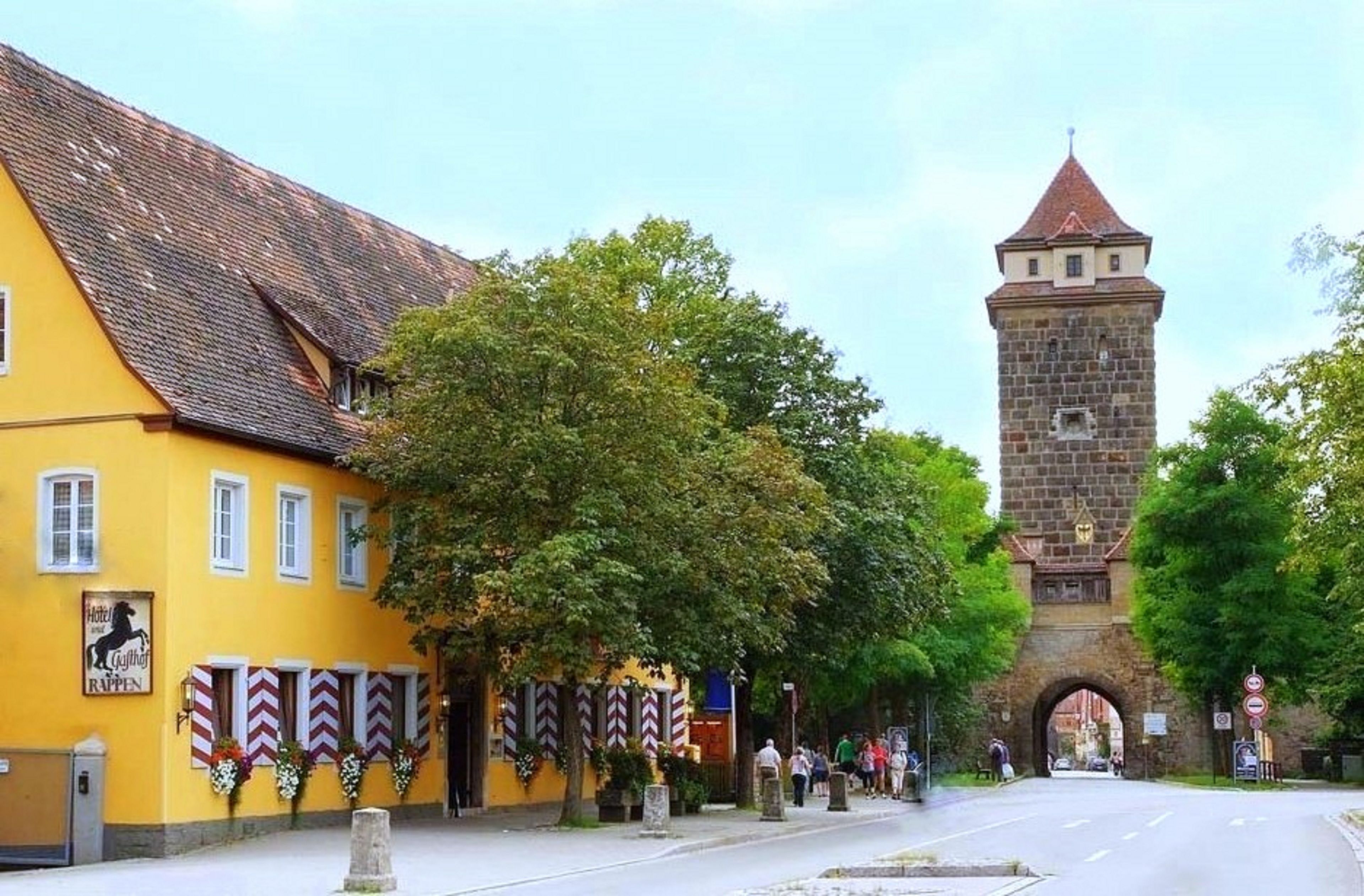 Ein gelbes Gebäude mit einem Hotelausleger und einem Stein-Turm im Hintergrund.