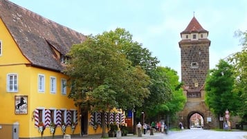 Ein gelbes Gebäude mit einem Hotelausleger und einem Stein-Turm im Hintergrund.