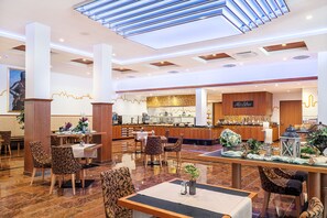 Un hall d’hôtel comprenant un bar, des espaces aménagés avec des sièges et un comptoir de réception.