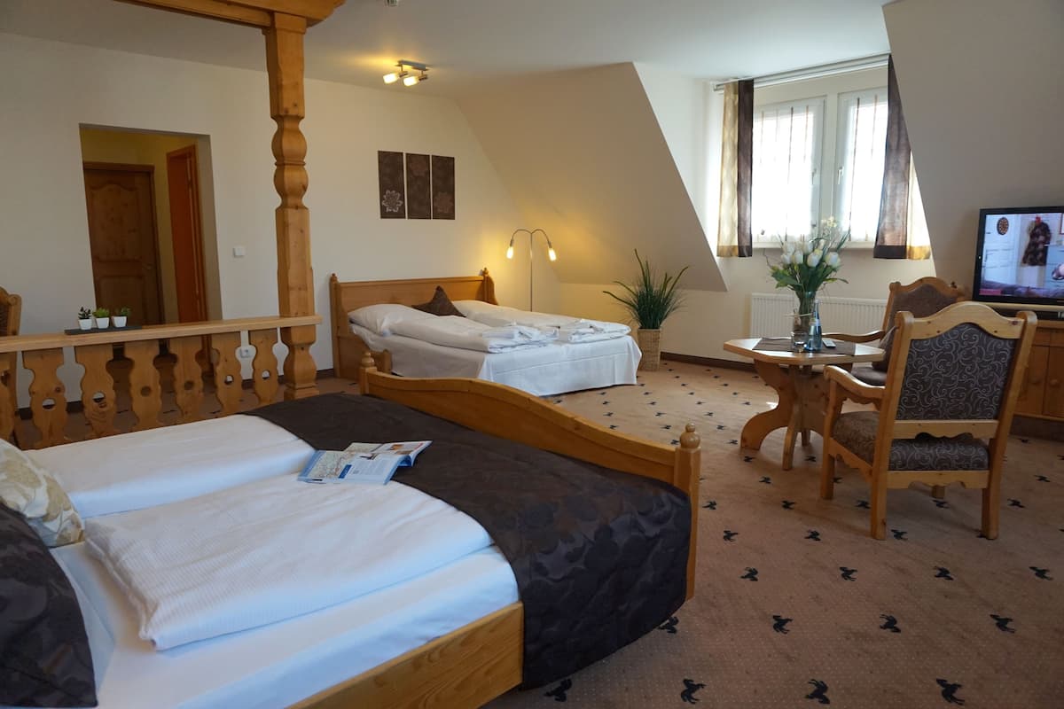 Ein Schlafzimmer mit zwei Betten, einem Holzbett, einem kleinen Tisch und einem Fernseher.