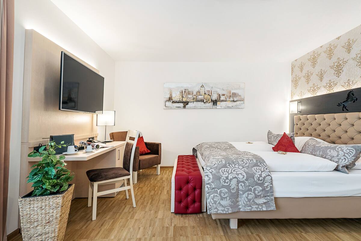 Ein modernes Hotelzimmer mit Bett, Schreibtisch, Stuhl und Flachbildfernseher.