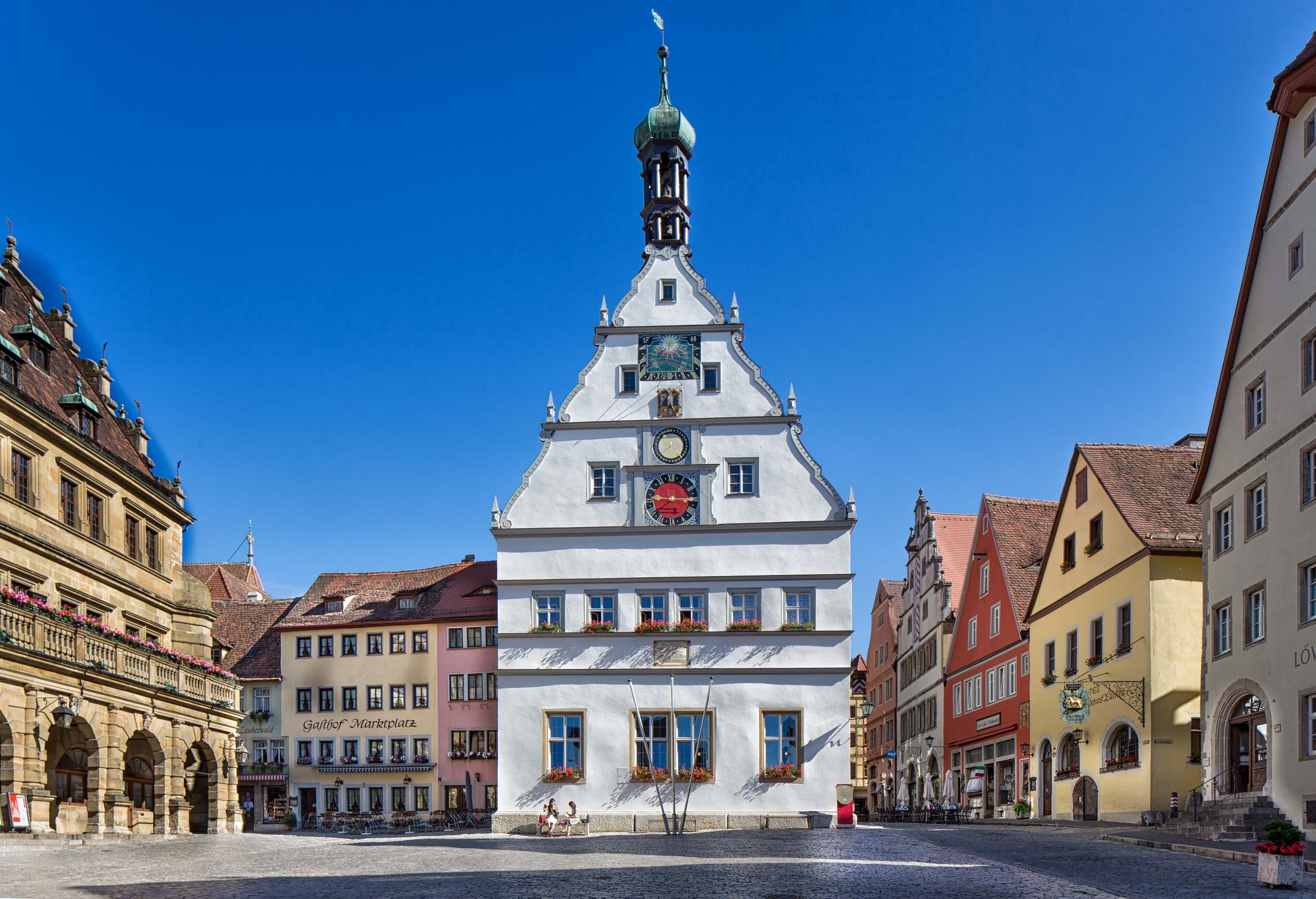 A historic building with a clock tower, arched windows, and a cobblestone street.
