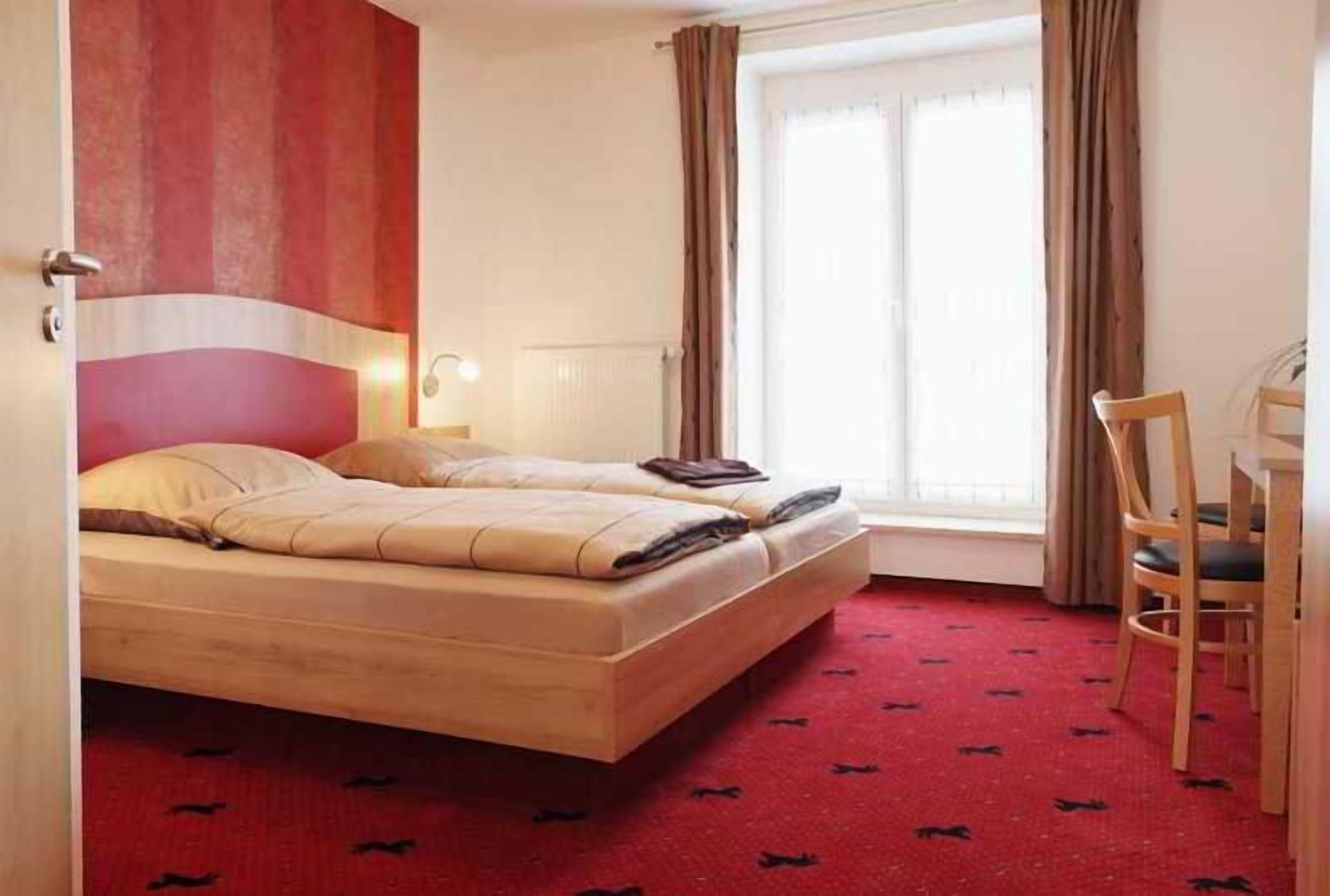 A hotel room with a bed, a desk, and a chair.
