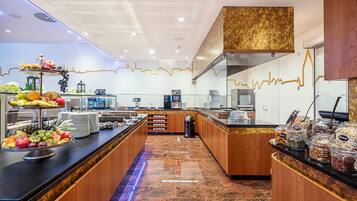A buffet area with a variety of fruits and snacks, a marble floor, and wooden accents.