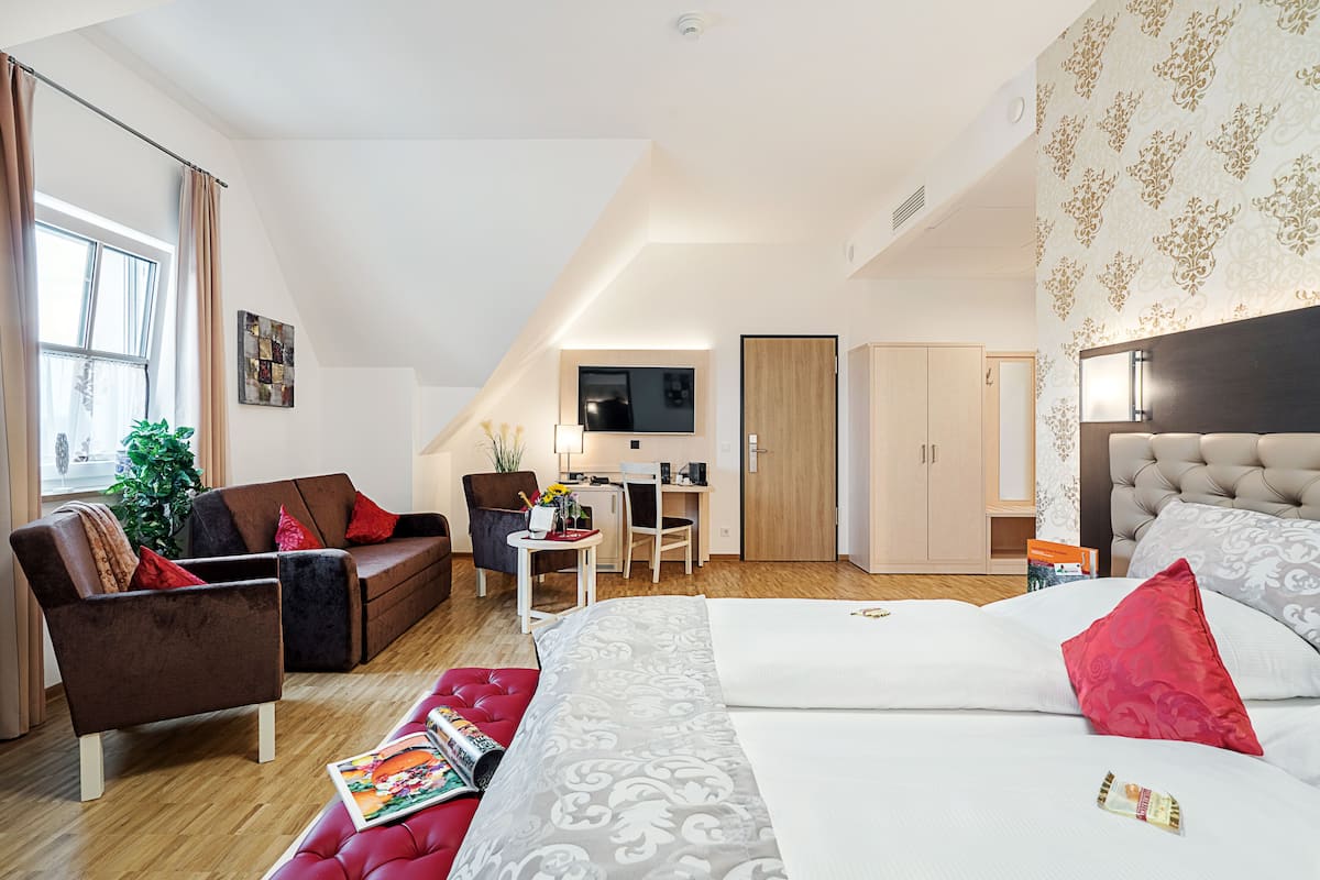 Ein modernes Hotelzimmer mit einem großen Bett, einer Couch, einem Schreibtisch und einem Sessel.