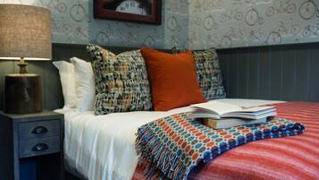 Un letto rifatto con una coperta a righe rosse e bianche, un libro e una coperta decorata.
