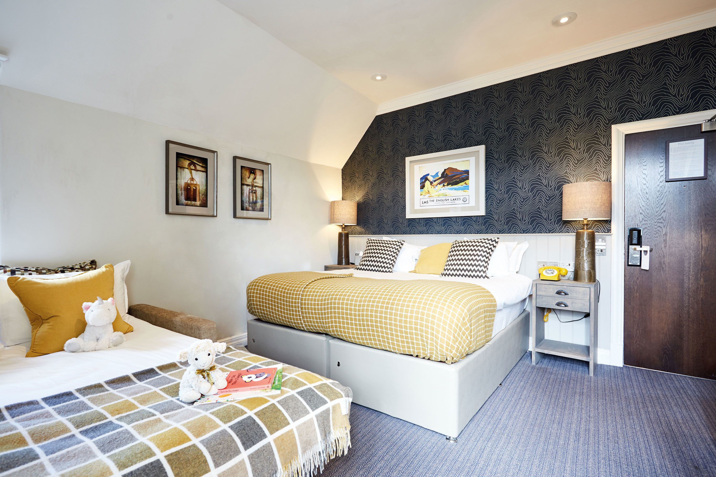A hotel room with a bed, bedside lamps, a nightstand, and a framed picture on the wall.