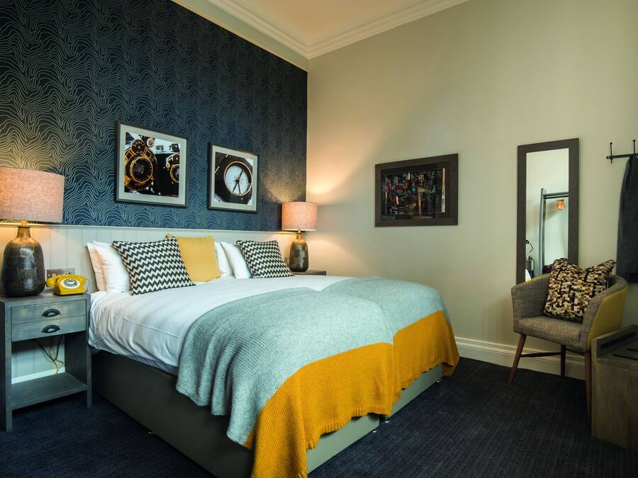 A bedroom with a bed, nightstands, a chair, and wall art.