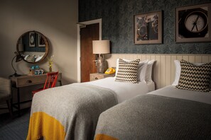 A hotel room with two beds, a desk with a chair, a lamp, a mirror, and a clock on the wall. - Toll House Inn (Lancaster)