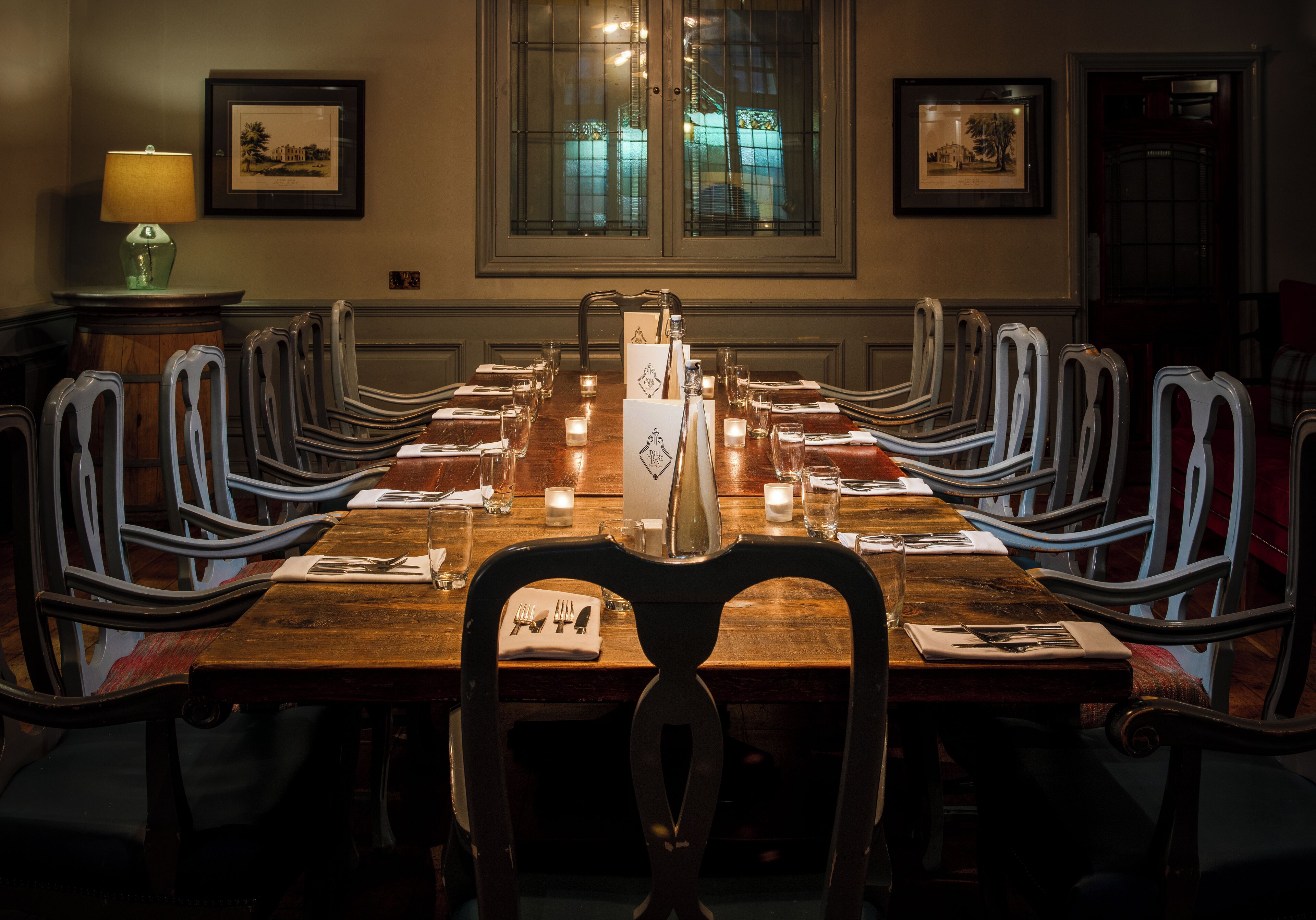Comedor con una larga mesa de madera dispuesta para una comida, rodeado de sillas de metal.