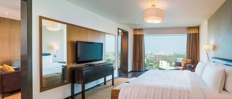 Una habitación de hotel moderna con una cama grande, un televisor de pantalla plana, un escritorio y vistas a la ciudad.