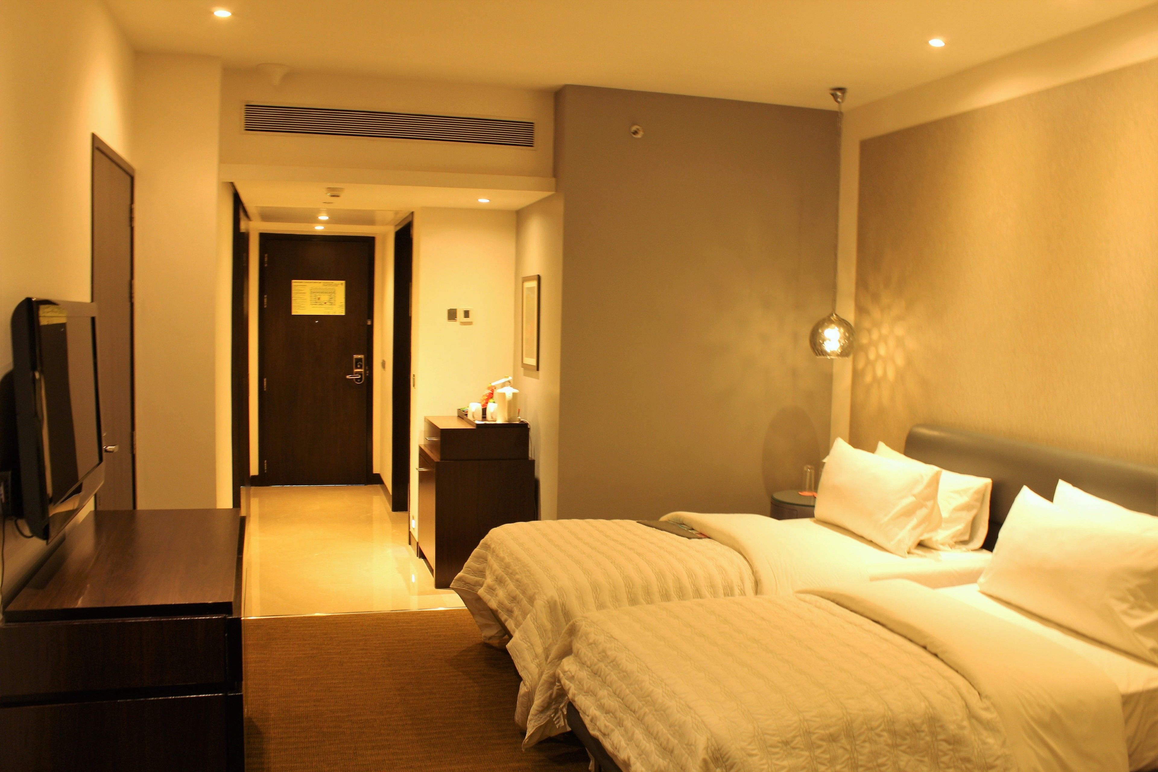 A hotel room with a bed, bedside table, and a television on a dresser.
