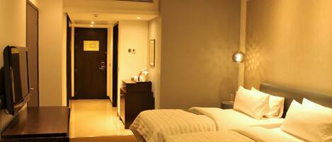 A hotel room with a bed, bedside table, and a television on a dresser.