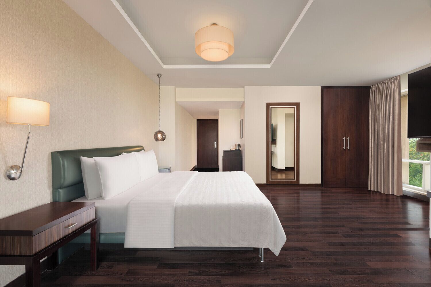 A hotel room with a large bed, a nightstand, a lamp, a wardrobe, and a television.