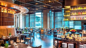 A spacious restaurant with high ceilings, modern lighting, and a variety of seating arrangements.
