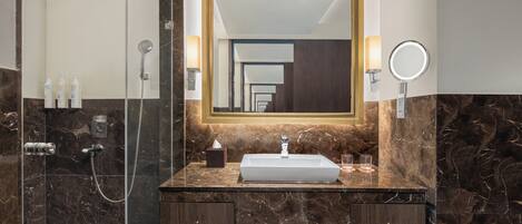 A bathroom with a glass-enclosed shower, a marble vanity with a sink, and a large mirror.