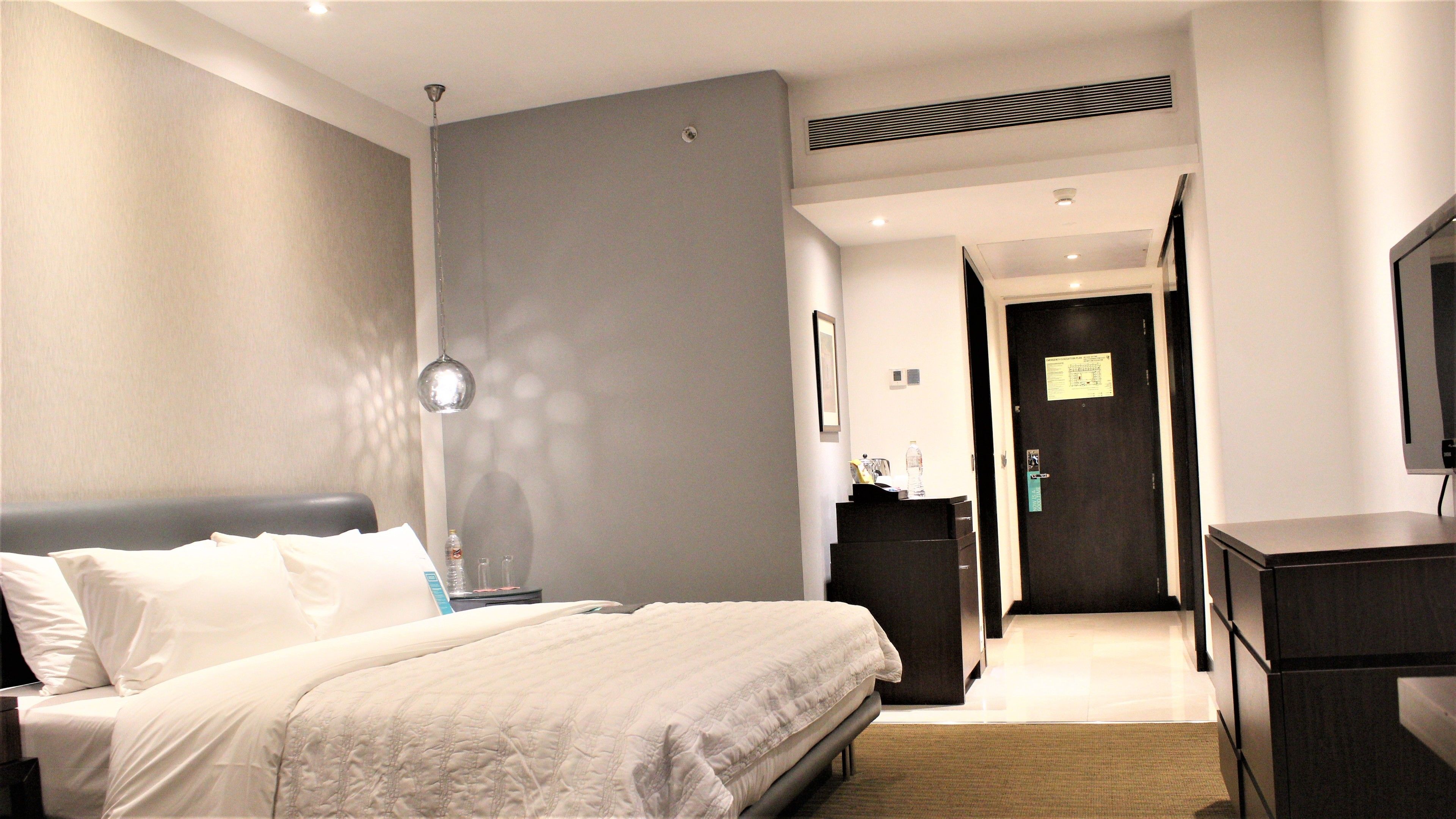 Ein Hotelzimmer mit Bett, Nachttisch, Lampe und Schreibtisch mit Stuhl.