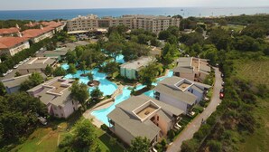 An aerial view of a resort with multiple buildings, a central swimming pool, and a view of the sea. - Sueno Hotels Beach Side (Manavgat)