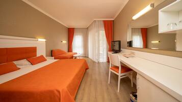 A hotel room with two beds, a desk, a chair, a television, and a trash bin.