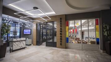 Un interior moderno con una recepción, una pantalla digital mostrando 'Sueno' y un restaurante con decoración colorida.