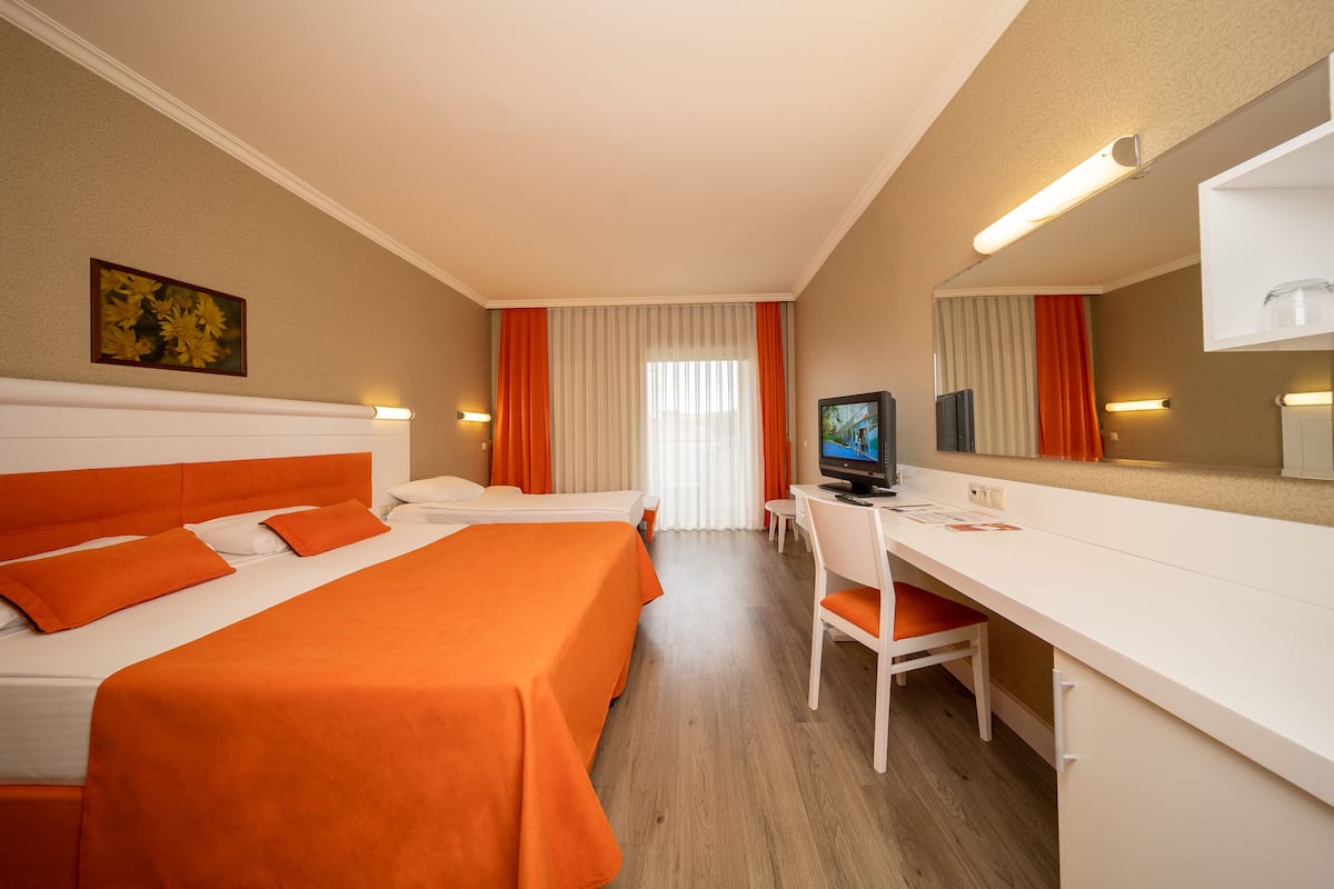 A hotel room with two beds, a desk, a chair, a television, and a large mirror.
