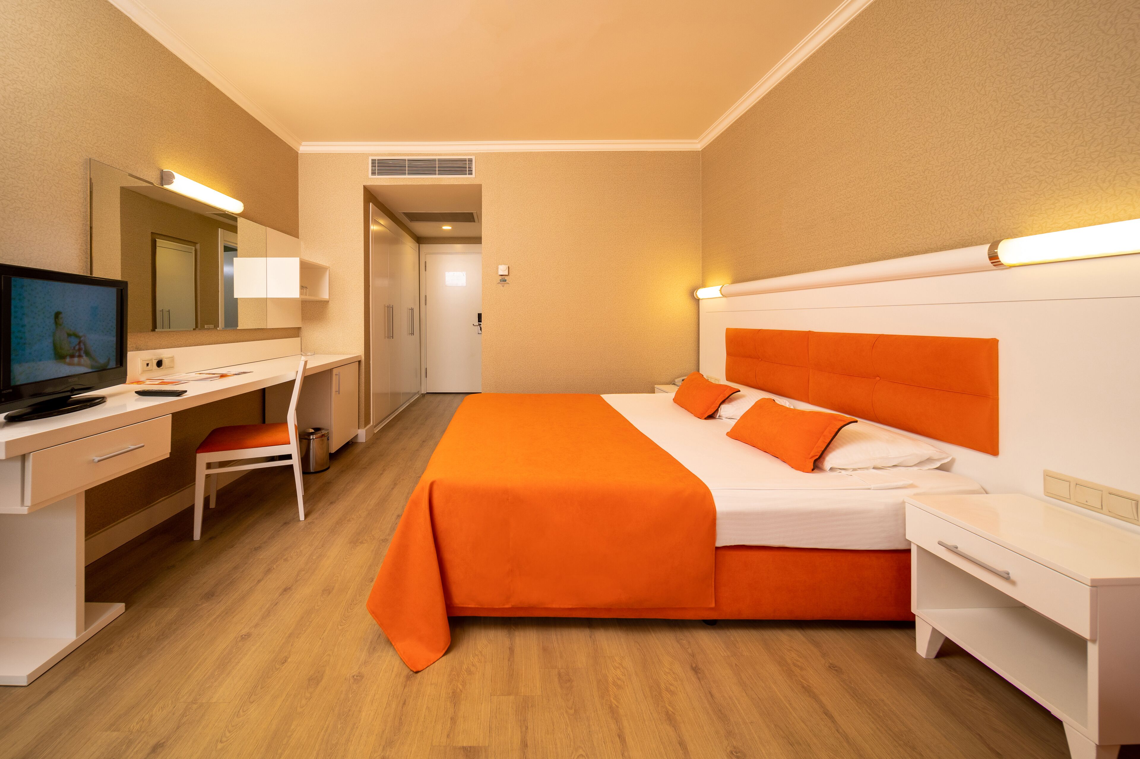 Habitación de hotel con cama, escritorio, silla, televisión y baño a la vista.