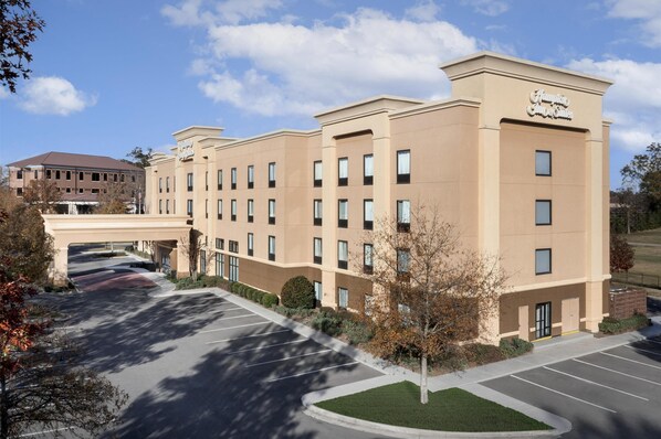A multi-story hotel with a beige facade, multiple windows, and a parking lot in front. - Hampton Inn & Suites Laurel, MS (Laurel)