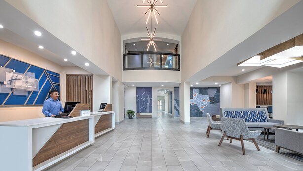 A spacious lobby with a reception desk, seating area, and a second-floor balcony. - Holiday Inn Express Hotel & Suites DALLAS WEST by IHG (Dallas)