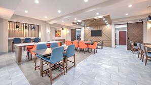 A modern conference room with multiple tables and chairs, a large screen, and a herringbone-patterned wall. - Holiday Inn Express Hotel & Suites DALLAS WEST by IHG (Dallas)