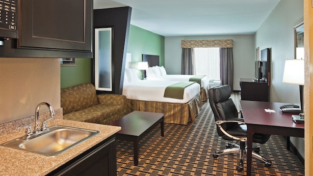 A hotel room with a kitchenette, a bed with a headboard, a desk with a chair, and a television. - Holiday Inn Express Hotel & Suites JACKSONVILLE by IHG (Jacksonville)