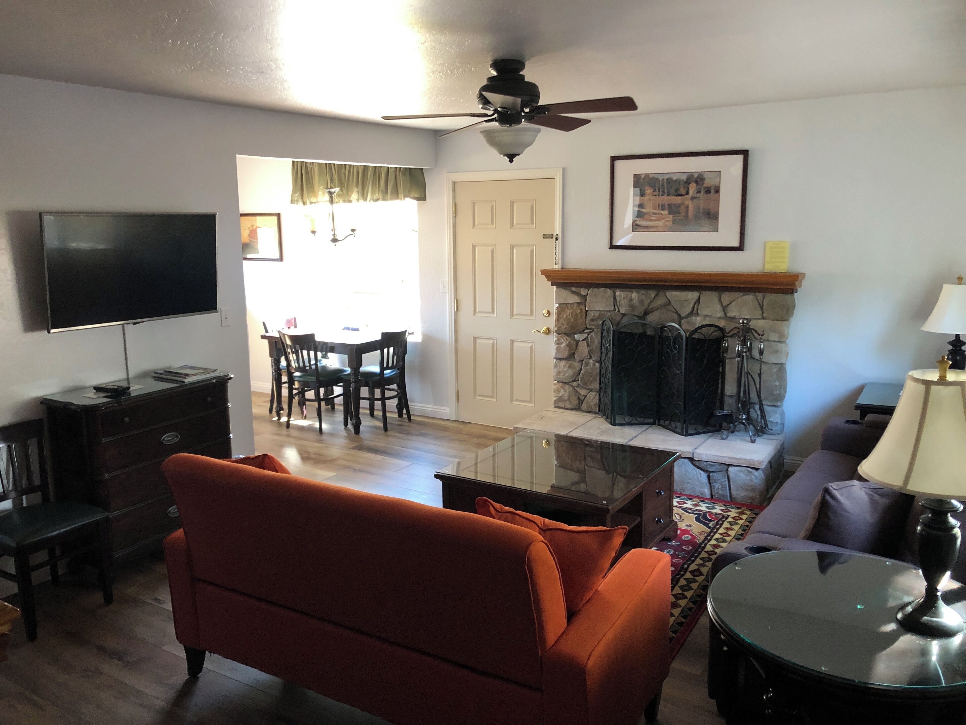 A living room with a sofa, a TV, a fireplace, and a dining area with chairs and a table.