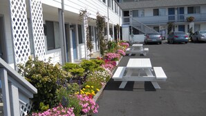 A row of white picnic tables with a flower garden and a building with an 'OFFICE' sign. - Super 8 by Wyndham Florence OR (Florence)
