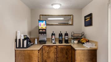 Uma cozinha compacta com máquina de café, dispensador de suco e dispensador de água.