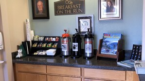 A reception desk with a coffee station, framed photos, and a sign that reads "Breakfast on the Run". - Super 8 by Wyndham Florence OR (Florence)