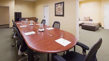 A conference room with a long table, chairs, and a sofa in the background.