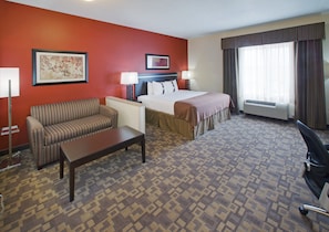 A hotel room with a bed, a sofa, a desk, and a chair.