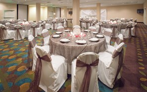 A banquet hall with round tables, chairs with sashes, and a carpeted floor. - Holiday Inn Lincoln Southwest by IHG (Lincoln)