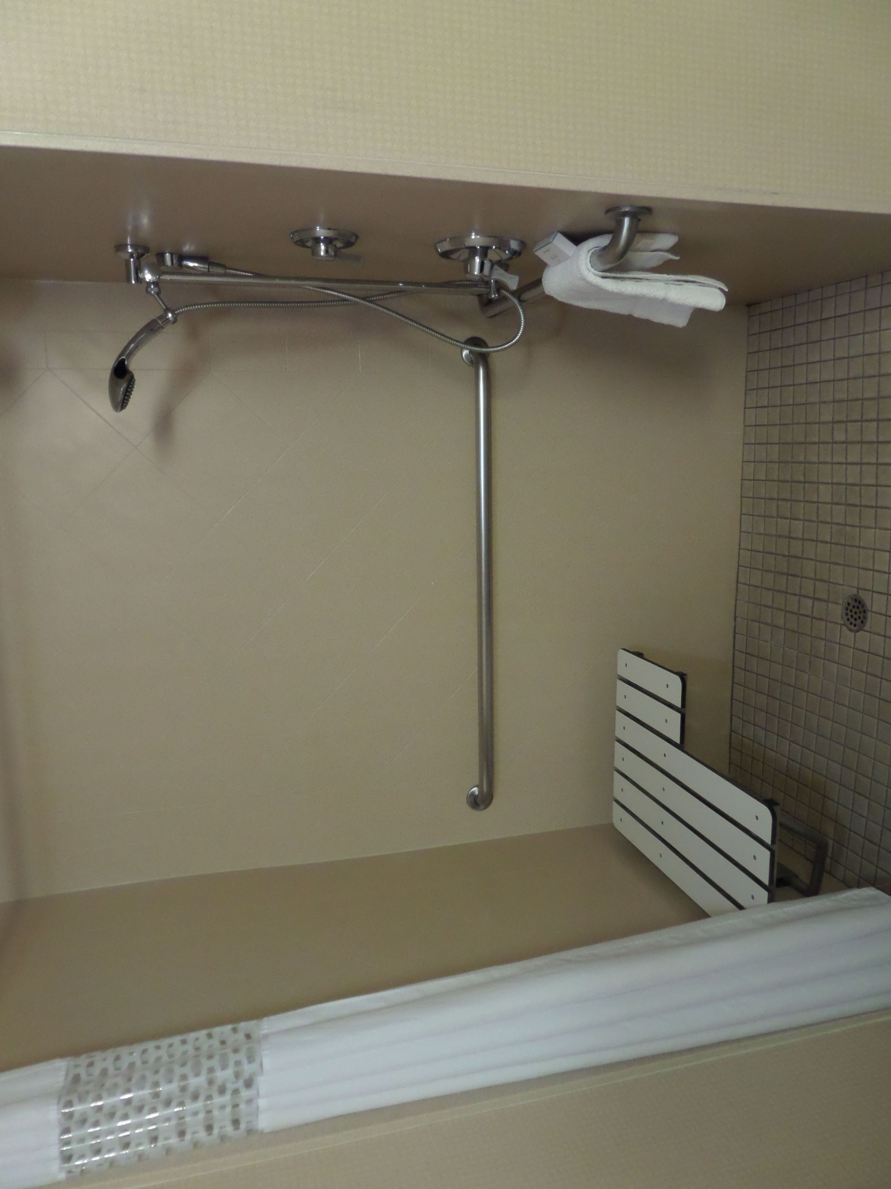 A bathroom with a bathtub, a showerhead, and a towel rack.