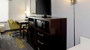A hotel room with a flat-screen TV on a wooden cabinet, a desk with a chair, a lamp, and a floor lamp. - Hampton Inn & Suites Bakersfield/Hwy 58, CA (Bakersfield)