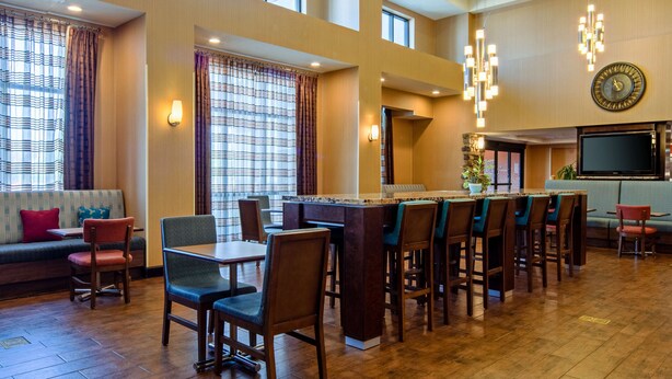 A hotel lobby with a bar area, seating, and a large screen. - Hampton Inn & Suites Bakersfield/Hwy 58, CA (Bakersfield)