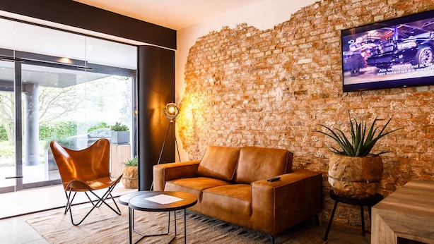 Un salon moderne avec un mur en briques, un canapé en cuir et un téléviseur fixé au mur.