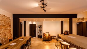 Un intérieur moderne avec une table à manger en bois, des tabourets de bar, un mur en briques et un luminaire contemporain.