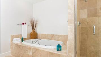 A modern bathroom with a freestanding bathtub, a shower area, and a towel rack with folded towels.
