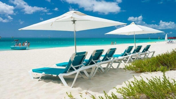 A beach with white umbrellas and blue lounge chairs. - Grandview on Grace Bay (Providenciales)