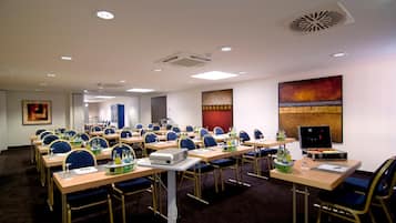 A conference room with rows of tables, chairs, and a projector.