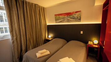 Habitación de hotel con dos camas, un cuadro en la pared y una ventana con cortinas.