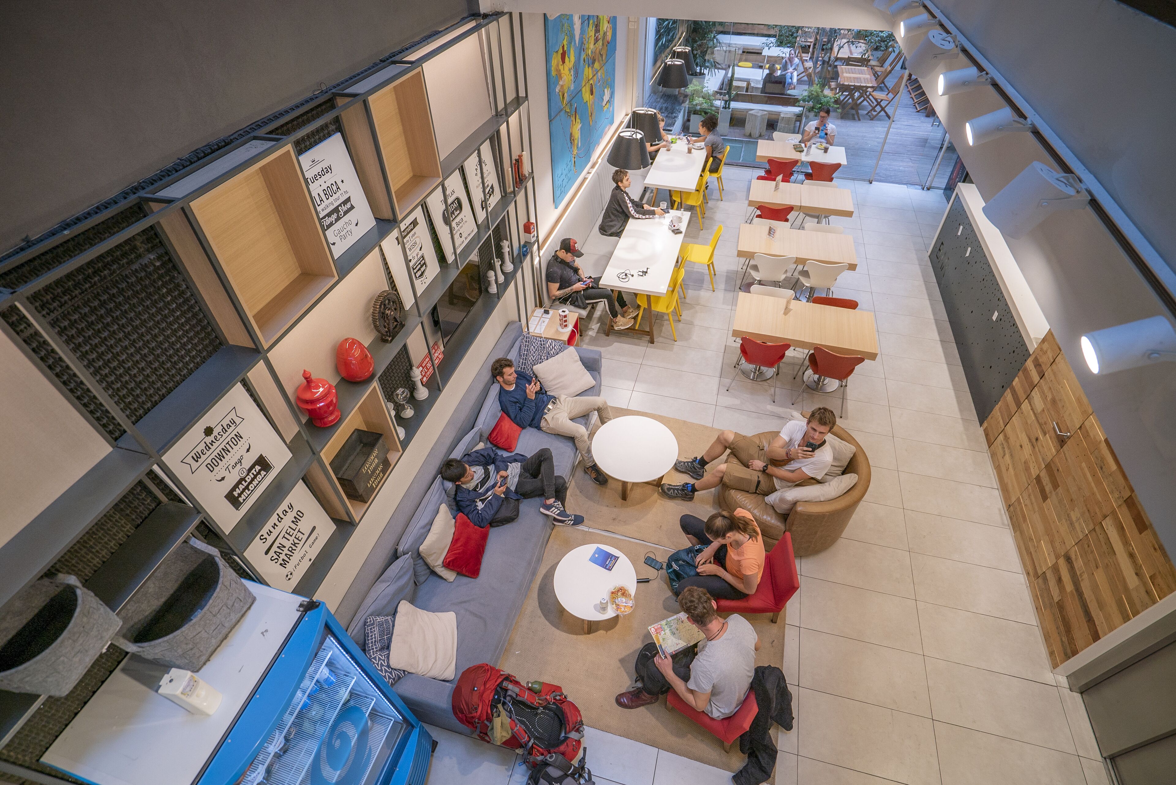Una cafetería moderna con diversas zonas de estar, incluyendo mesas redondas y sofás, y una variedad de opciones de asiento.