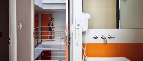 A hotel room with a bunk bed, a bathroom with an orange-tiled wall, and a white sink.